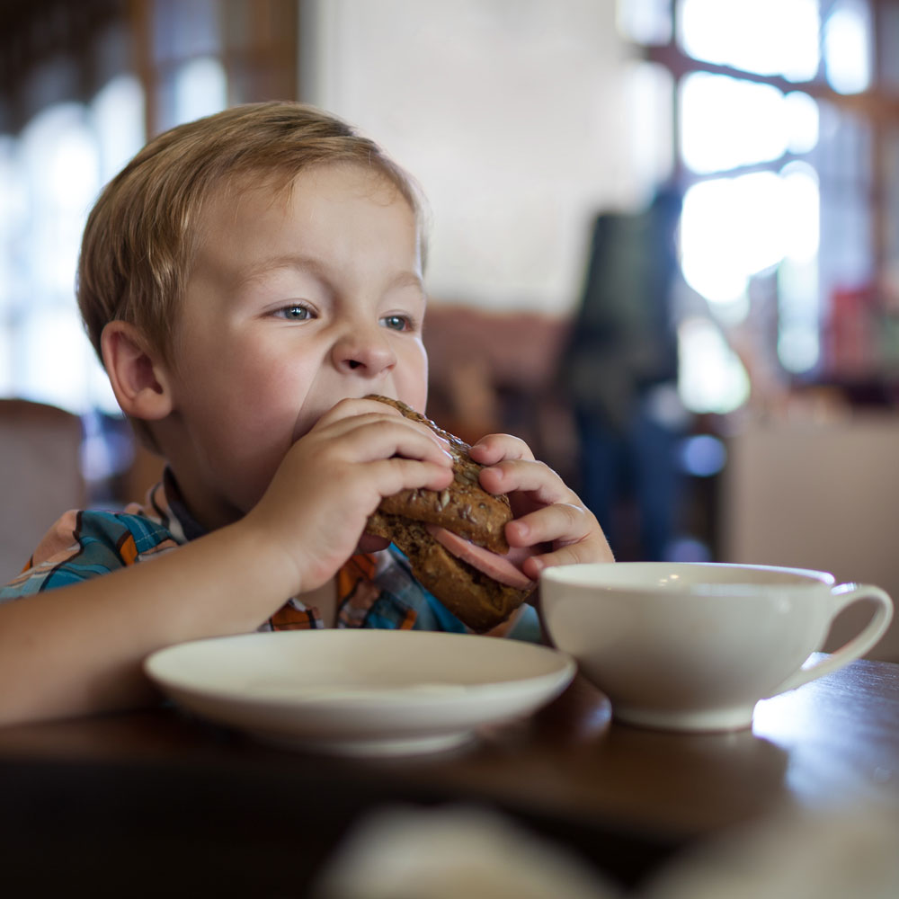 Little boy eating a sandwich in a cafe - Paediatric Dietitian